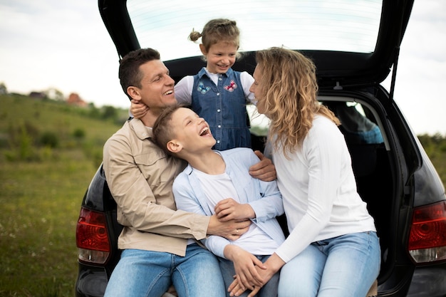 Família feliz com carro em plano médio