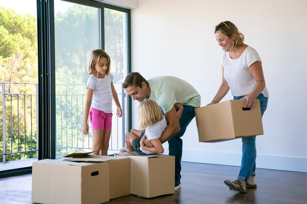 Família feliz com crianças perto de caixas de papelão em pé na sala de estar