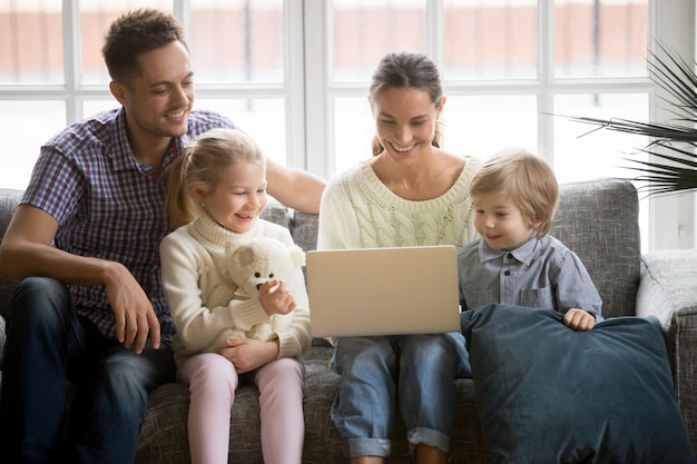 Família feliz, com, crianças, tendo divertimento, usando computador portátil, ligado, sofá