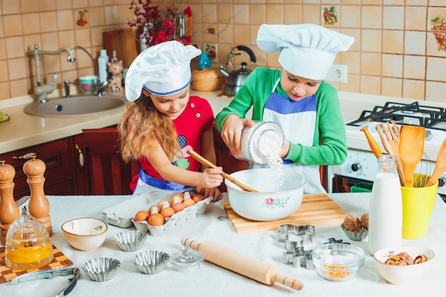 Família feliz, crianças engraçadas estão preparando a massa, assar biscoitos na cozinha