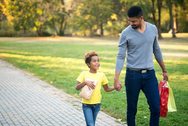 Família feliz de mãos dadas e caminhando juntos no parque