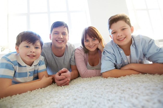 Família feliz deitada em um tapete branco