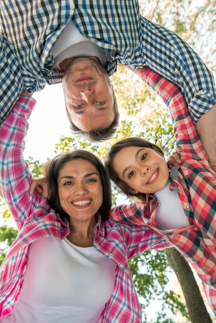 Foto grátis família feliz formando amontoado no parque contra o céu