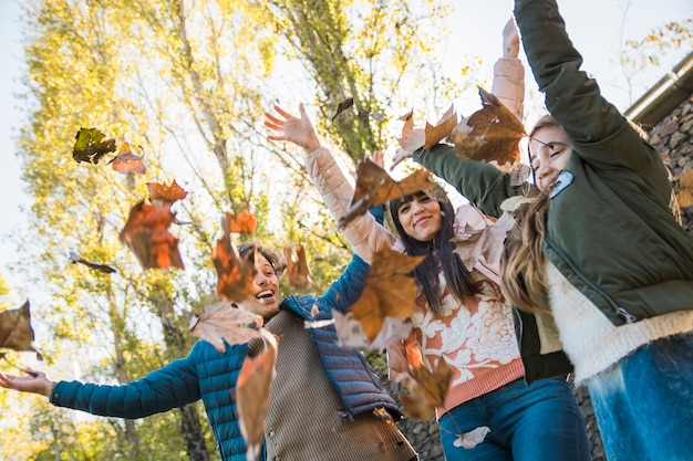 Família feliz jogando Outono folhas ao redor no parque