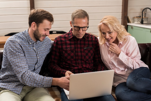 Família feliz olhando para laptop no sofá