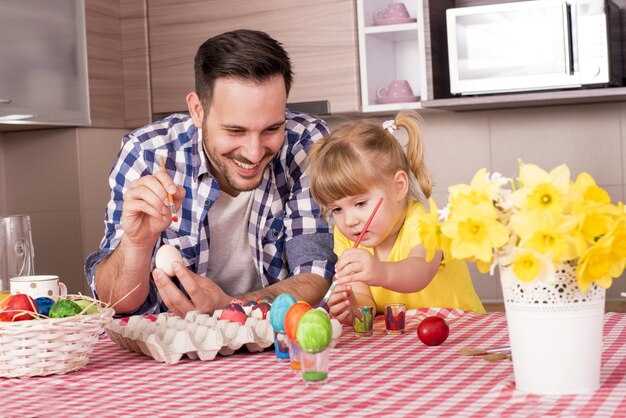 Família feliz pintando ovos de Páscoa com alegria