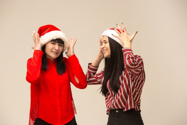 Família feliz posando de suéter de Natal. Desfrutando de abraços de amor, pessoas de férias. Mãe e filha em um fundo cinza no estúdio