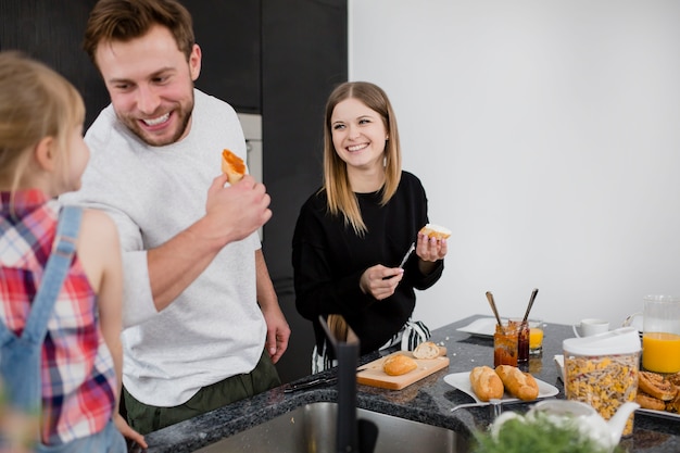 Família feliz preparando sanduíches abertos