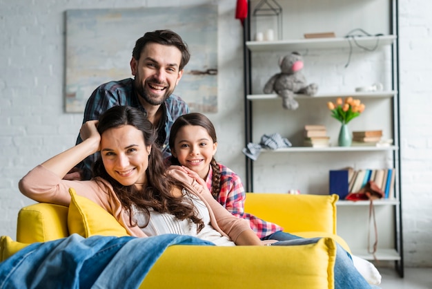 Família feliz sentada no sofá na sala de estar