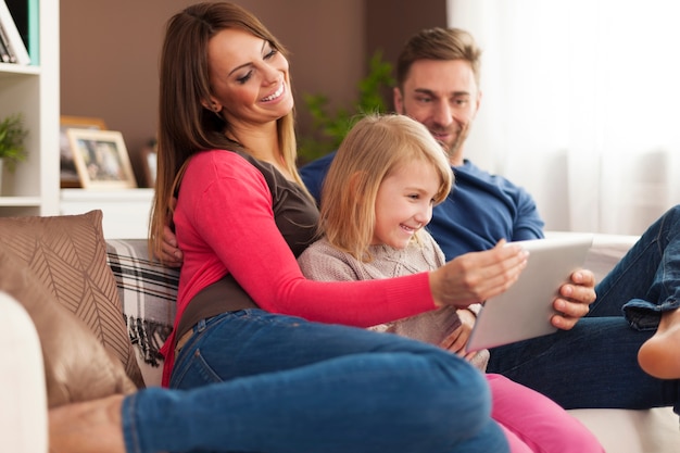 Família feliz usando tablet digital em casa