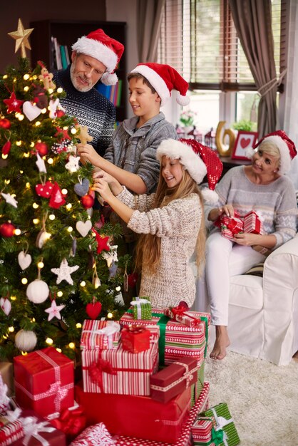 Família inteira enfeitando uma árvore de natal
