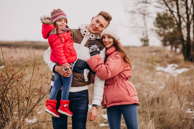 Família jovem caminhando juntos na floresta no inverno