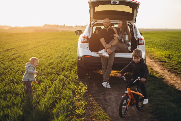 Família jovem com crianças que viajam de carro, parou no campo