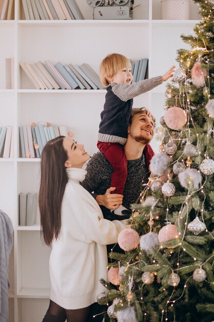 Família jovem com filho pequeno a decorar a árvore de natal