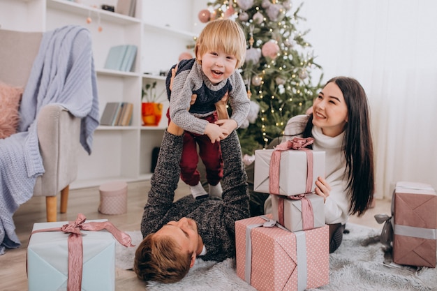 Família jovem com filho pequeno pela árvore de Natal