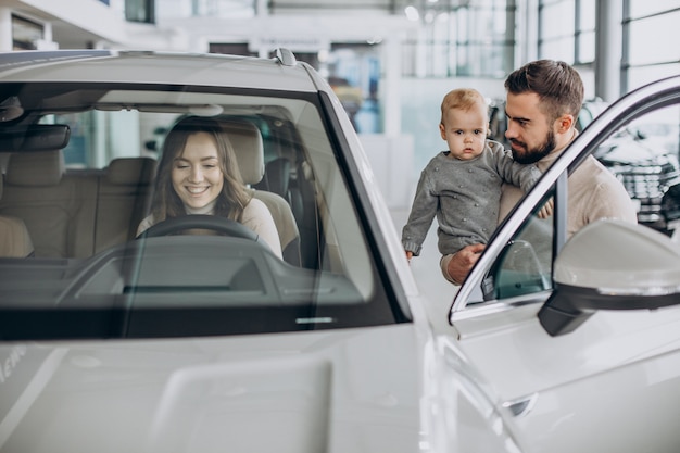 Foto grátis família jovem com uma menina escolhendo um carro