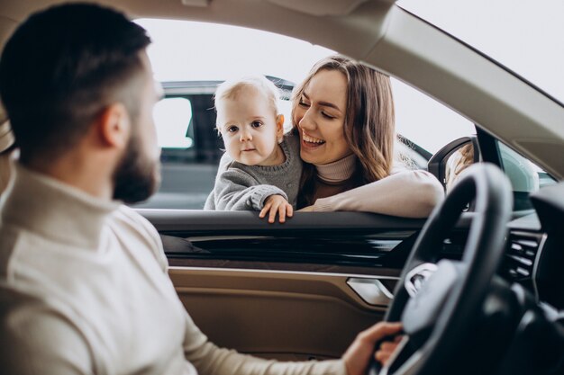 Família jovem com uma menina escolhendo um carro