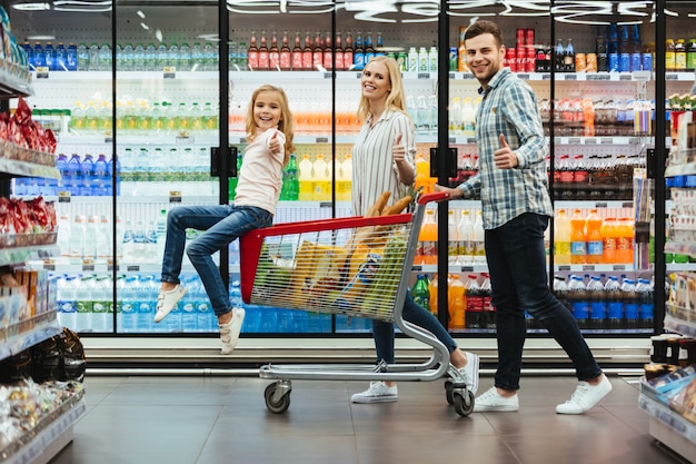 Família jovem feliz com uma criança sentada em um carrinho