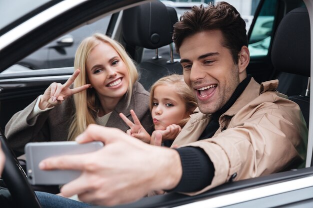 Família jovem feliz faz selfie pelo telefone móvel.