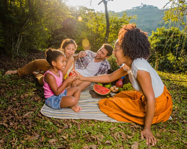 Família jovem sentada em pano de piquenique