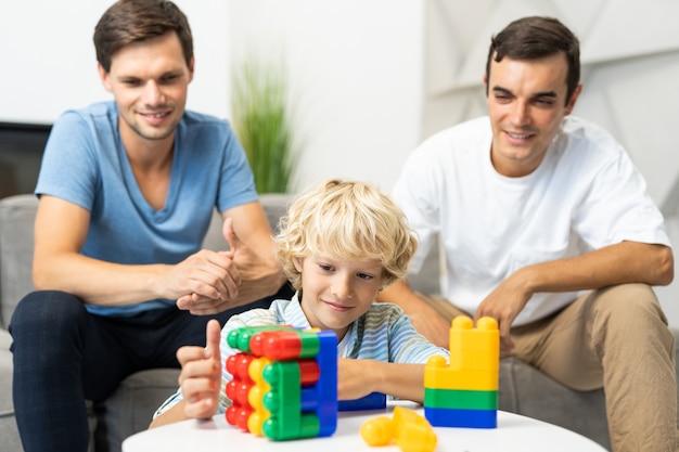 Família lgbt, casal gay com filho adotivo - pais homossexuais com filho se divertindo em casa