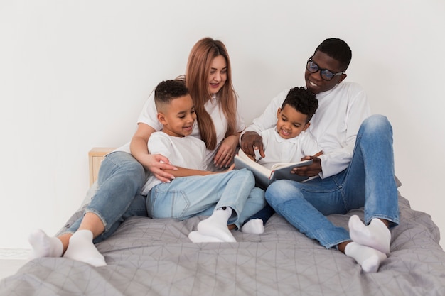 Família multicultural feliz se divertindo juntos na cama