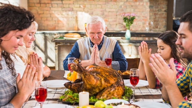 Família na mesa rezando antes de comer