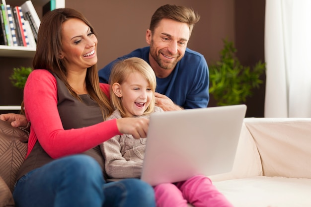 Família rindo junta e usando laptop em casa