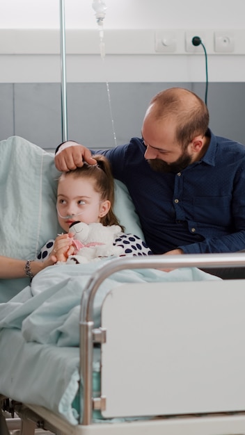 Foto grátis família sentada ao lado da filha doente hospitalizada discutindo tratamento de recuperação de medicação