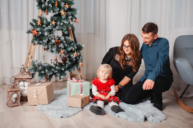 Família sentada em casa perto de árvore de Natal