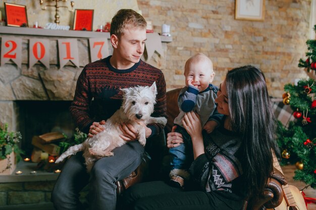 Família sentada em uma única poltrona com seu cão e seu bebê