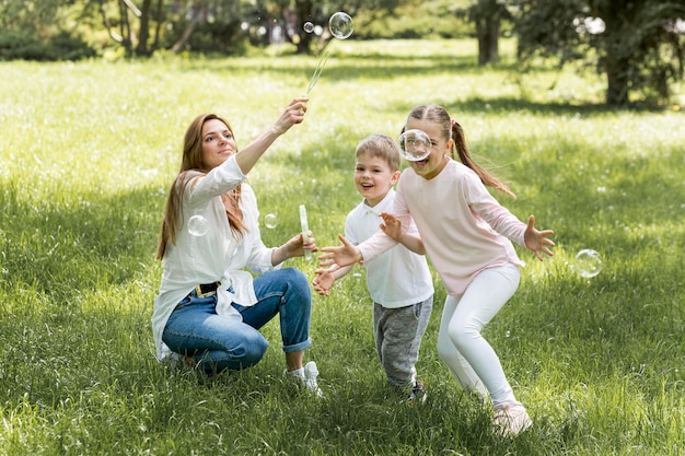 Foto grátis família soprando bolhas no parque