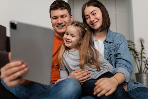 Família sorridente com foto média e laptop