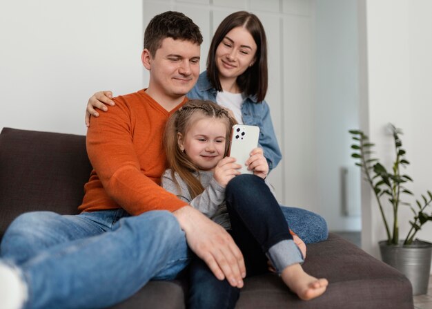 Família sorridente de plano médio com telefone