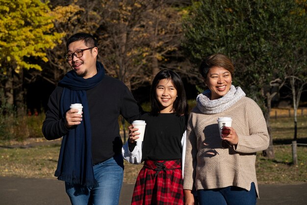 Família sorridente em plano médio caminhando junta