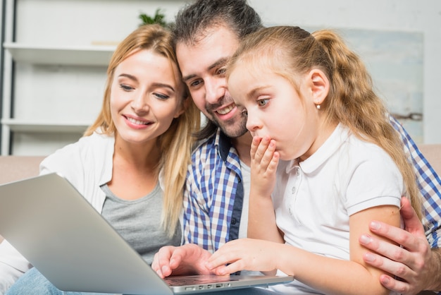 Família usando o laptop no sofá