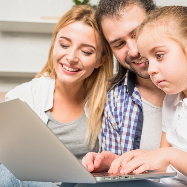 Família usando o laptop no sofá