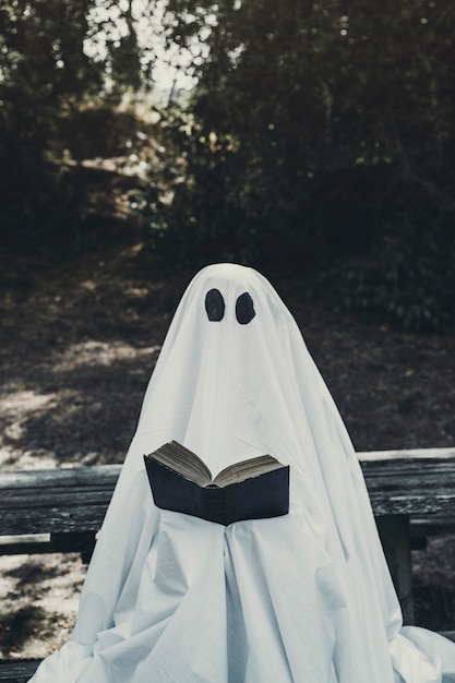 Fantasma sentado no banco e lendo o livro