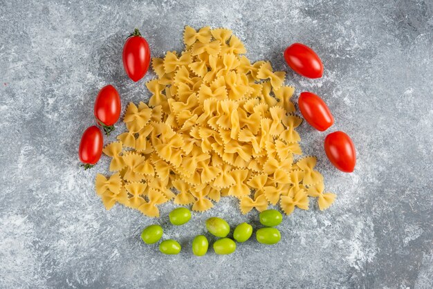 Farfalle e tomate crus no mármore.