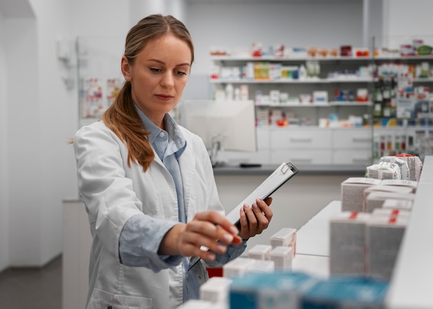 Farmacêutico feminino verificando remédio com prancheta