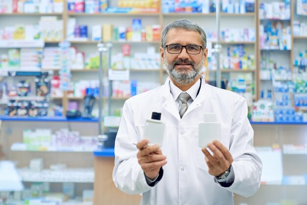 Farmacêutico masculino mostrando dois produtos na farmácia