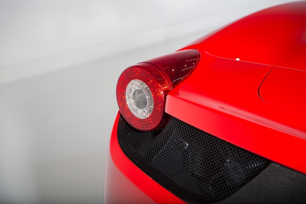 Farol da trilha de um carro esporte vermelho nos quartos brancos