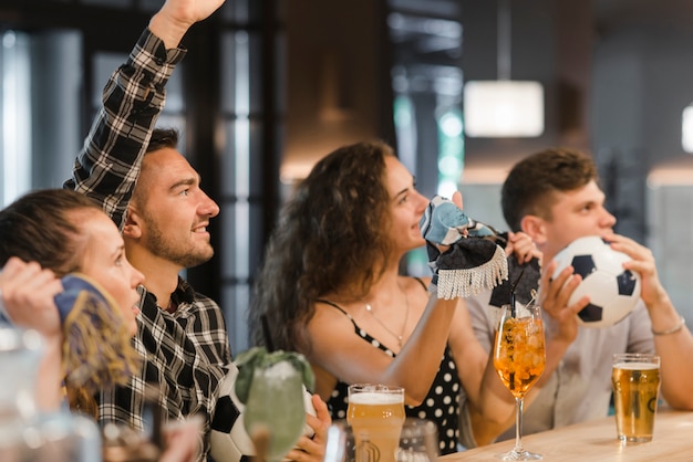 Fãs assistindo jogo de futebol na televisão no bar