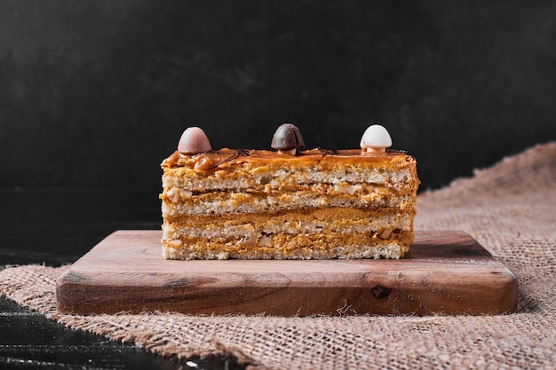 Fatia de bolo de caramelo em uma travessa de madeira.