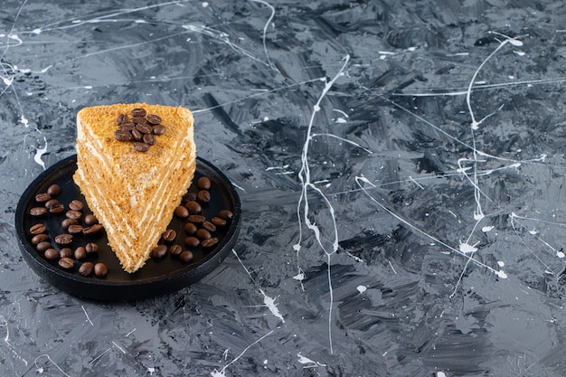 Fatia de bolo de mel em camadas com grãos de café colocados sobre uma mesa de mármore.