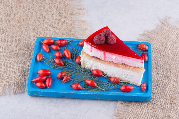 Fatia de bolo de queijo com roseiras frescas na placa azul.