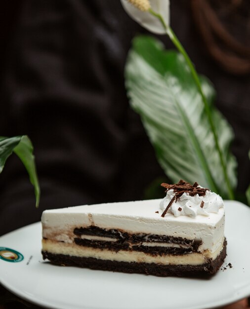 Fatia de cheesecake de baunilha chocolate em um prato branco.