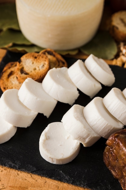 Fatia de queijo de cabra saboroso e pão na ardósia de pedra