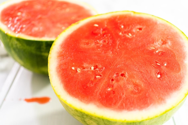 Fatiar a melancia sem sementes vermelha em uma placa de corte branca.