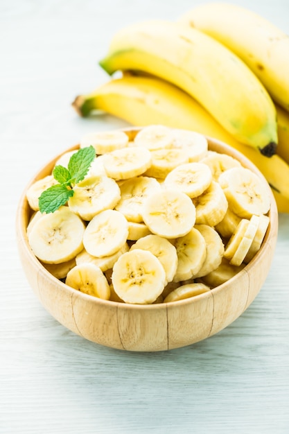 Foto grátis fatias de banana amarela crua na tigela de madeira